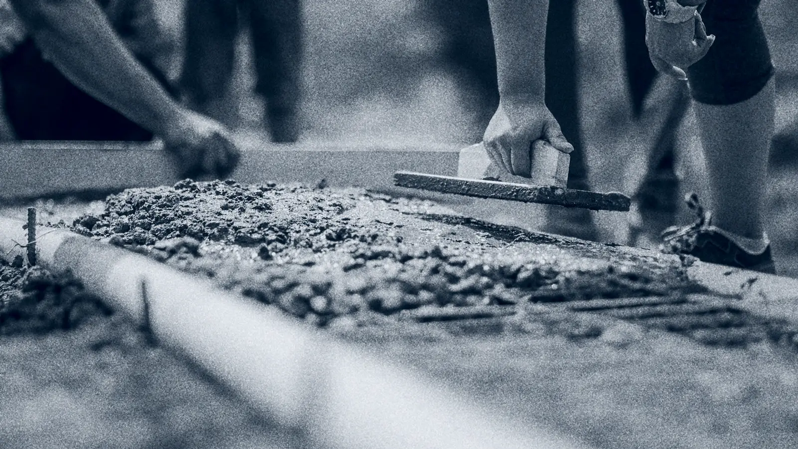 Construction crew finishing concrete on an active jobsite, contractor insurance from ALKEME